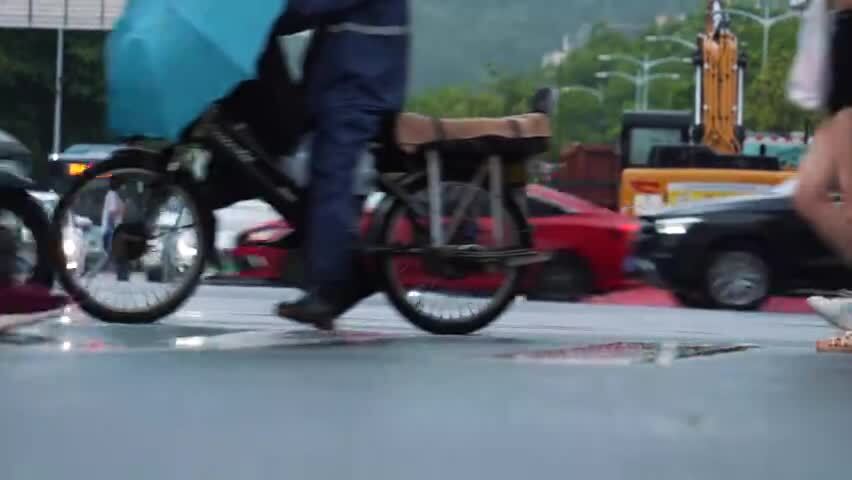 下雨天撑伞过马路的行人脚步特写
