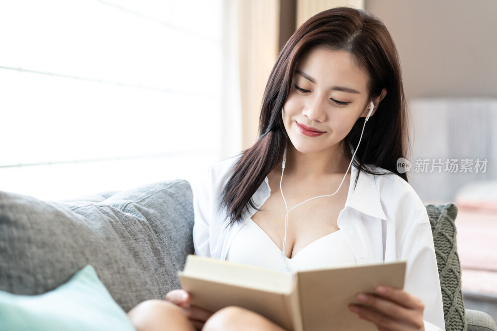 年轻女子在沙发上看书听音乐
