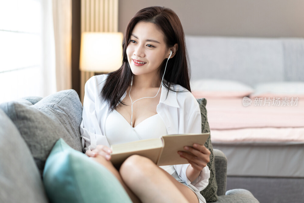 年轻女子在沙发上看书听音乐