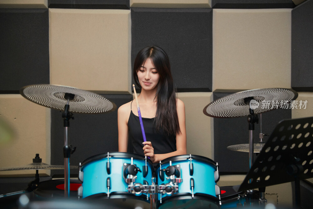 在排练室打爵士鼓的亚洲少女