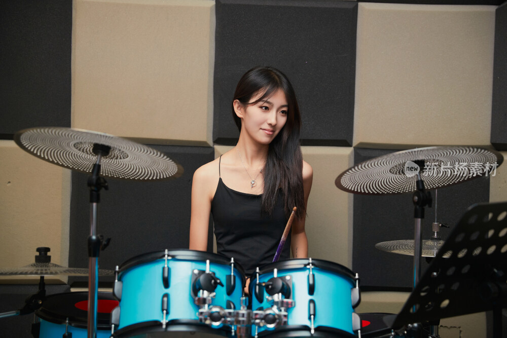 在排练室打爵士鼓的亚洲少女