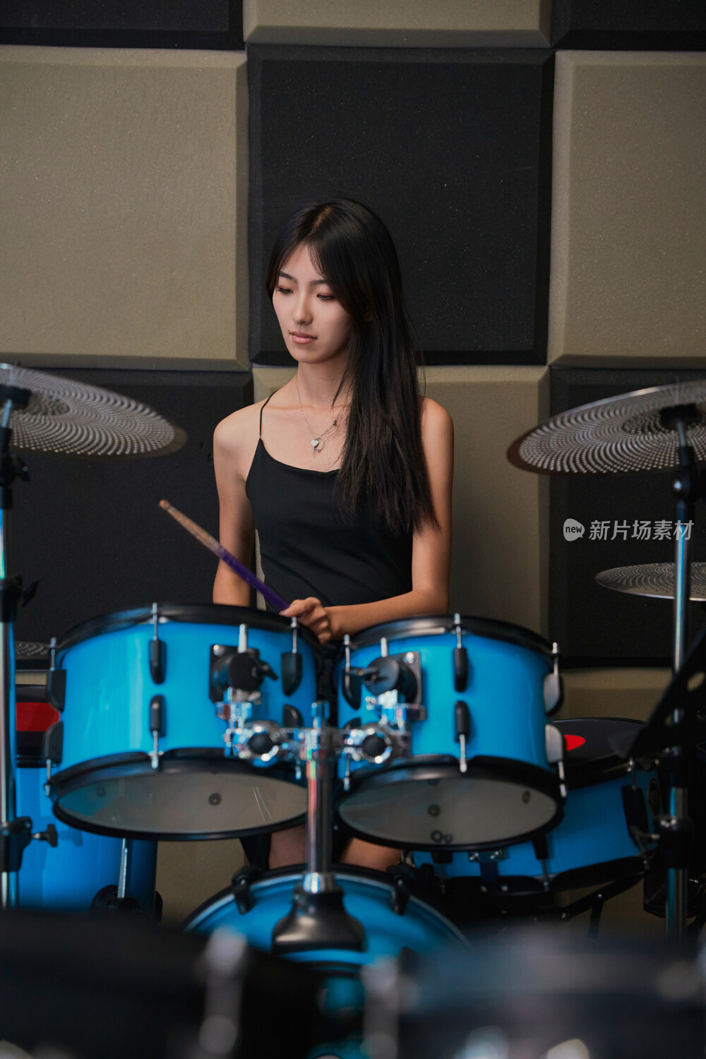 在排练室打爵士鼓的亚洲少女