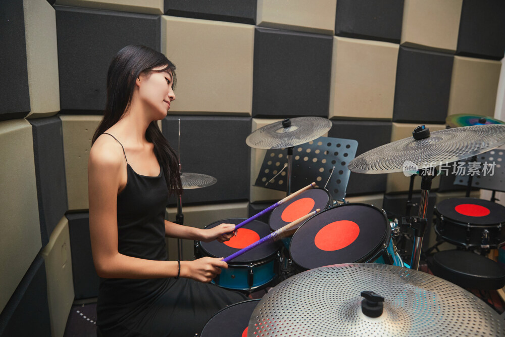 在排练室打爵士鼓的亚洲少女