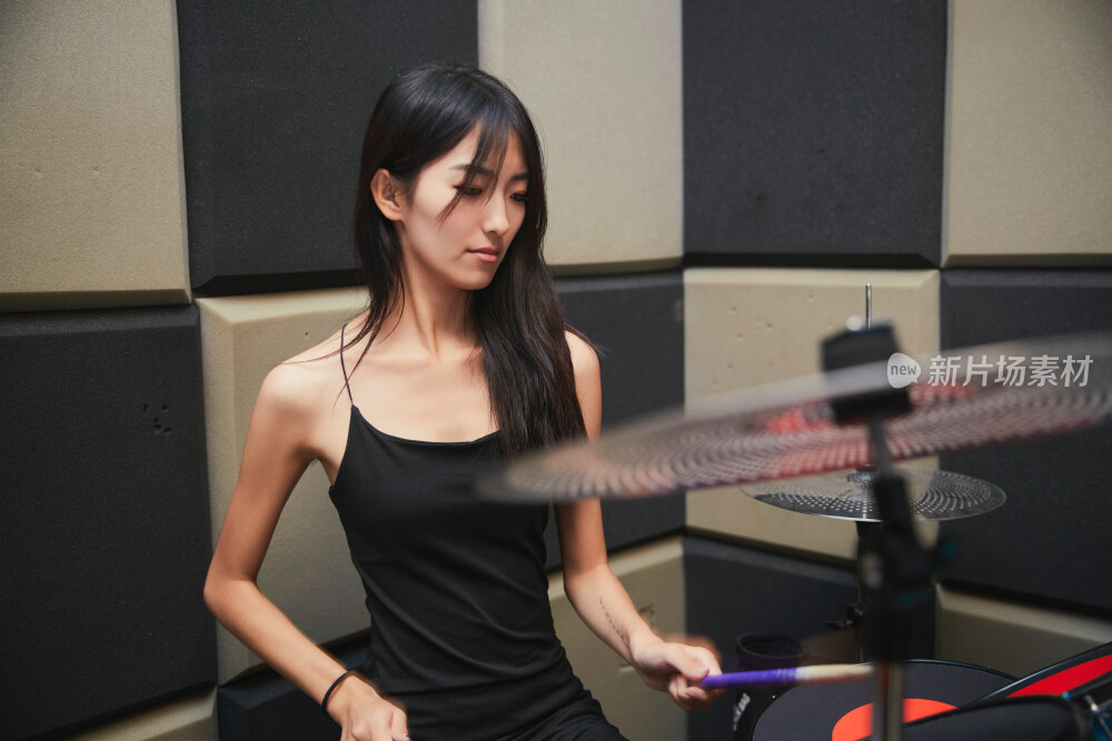 在排练室打爵士鼓的亚洲少女