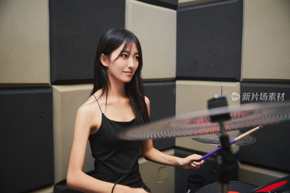 在排练室打爵士鼓的亚洲少女