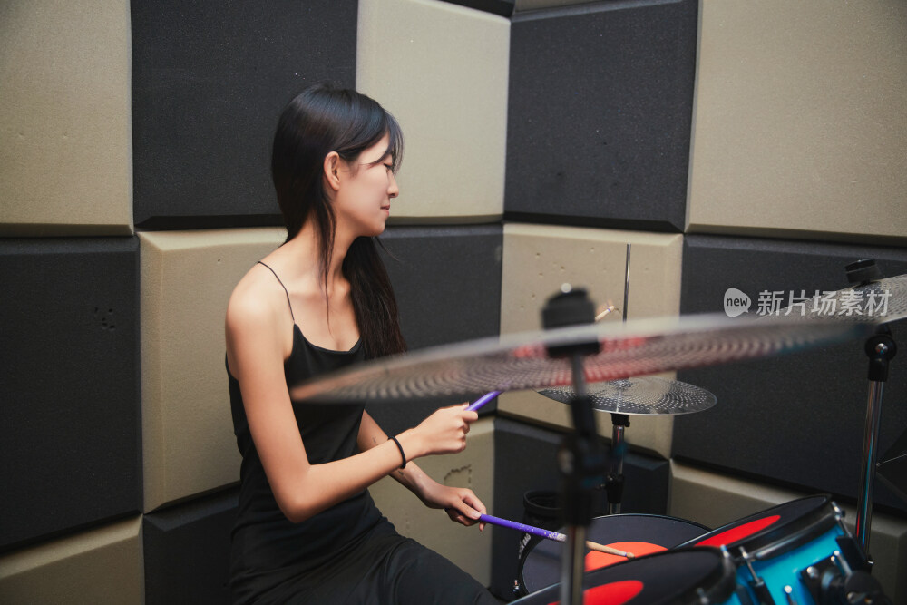 在排练室打爵士鼓的亚洲少女