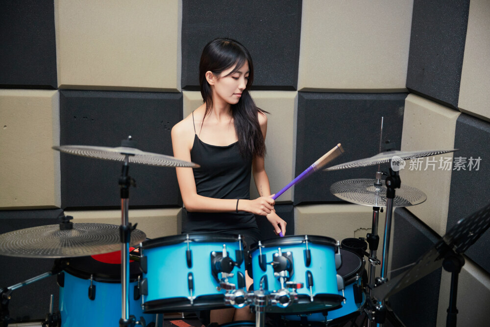 在排练室打爵士鼓的亚洲少女