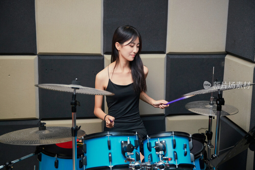 在排练室打爵士鼓的亚洲少女