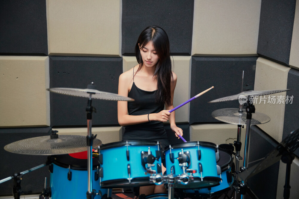 在排练室打爵士鼓的亚洲少女
