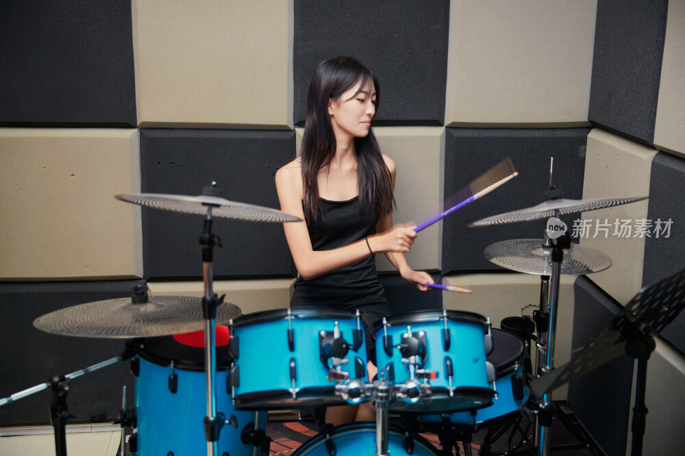 在排练室打爵士鼓的亚洲少女