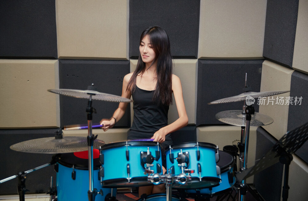 在排练室打爵士鼓的亚洲少女