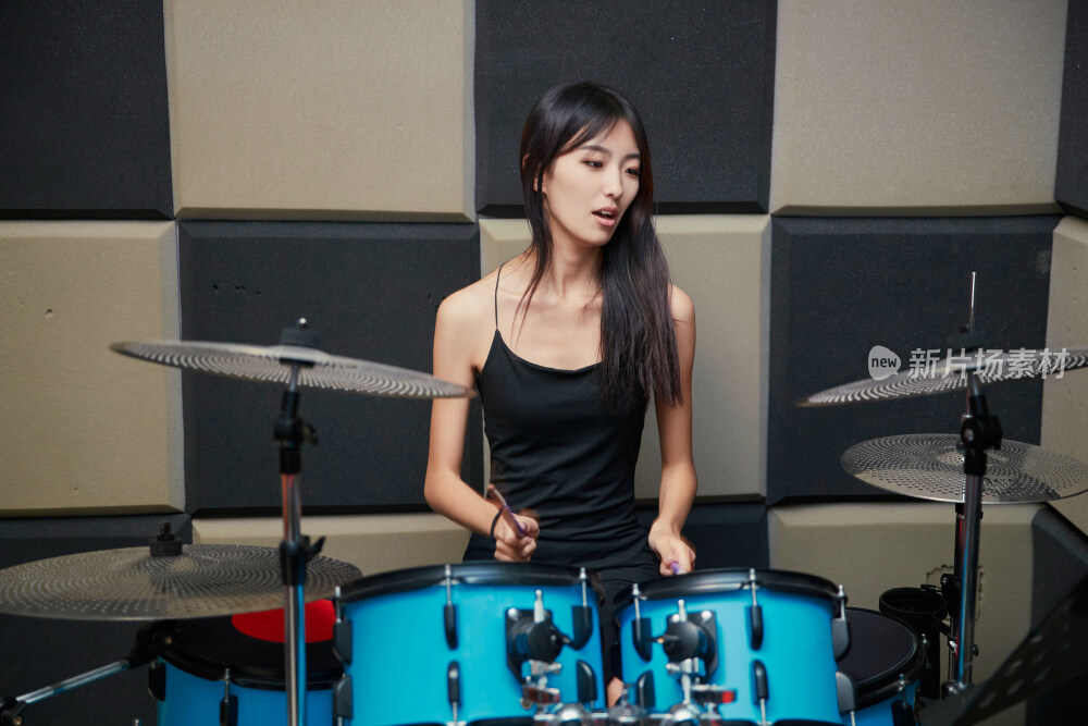 在排练室打爵士鼓的亚洲少女