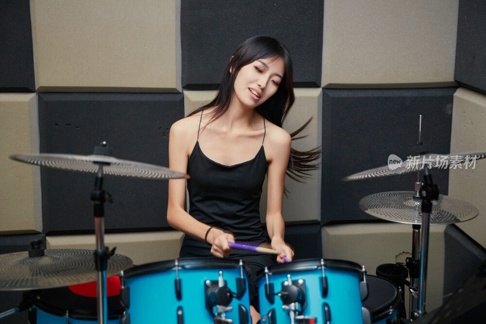 在排练室打爵士鼓的亚洲少女
