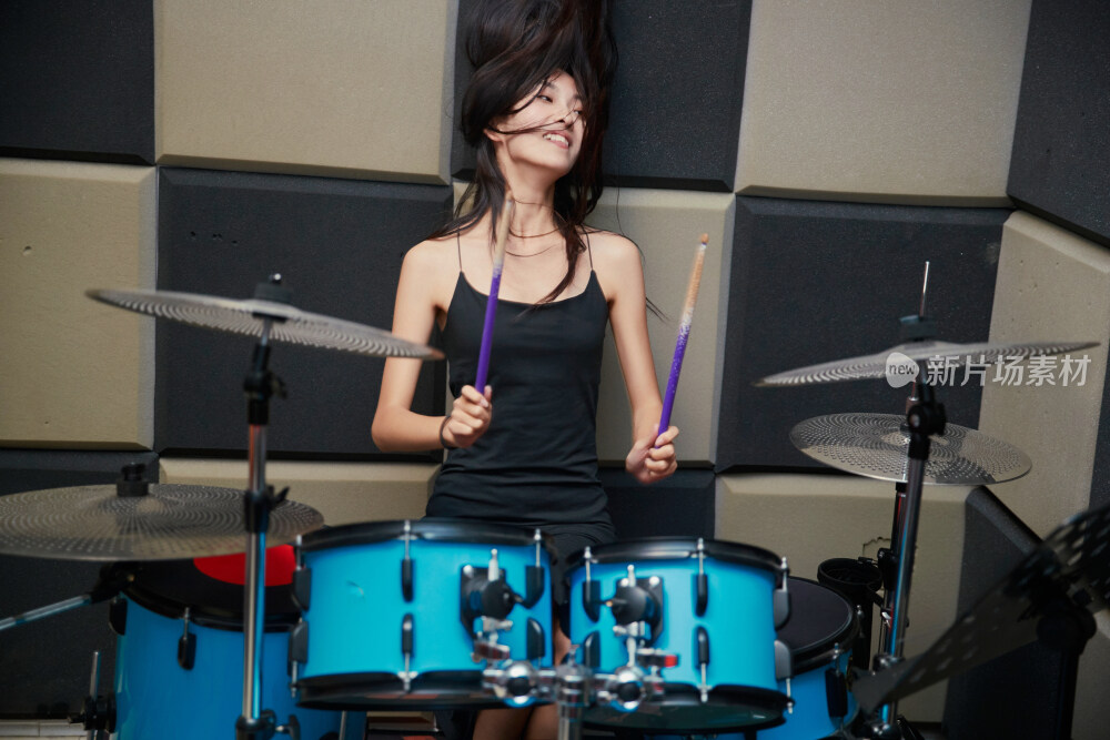 在排练室打爵士鼓的亚洲少女
