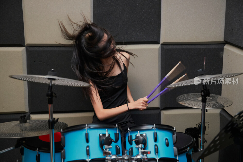 在排练室打爵士鼓的亚洲少女