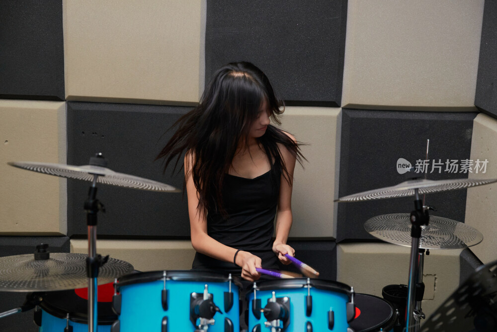 在排练室打爵士鼓的亚洲少女