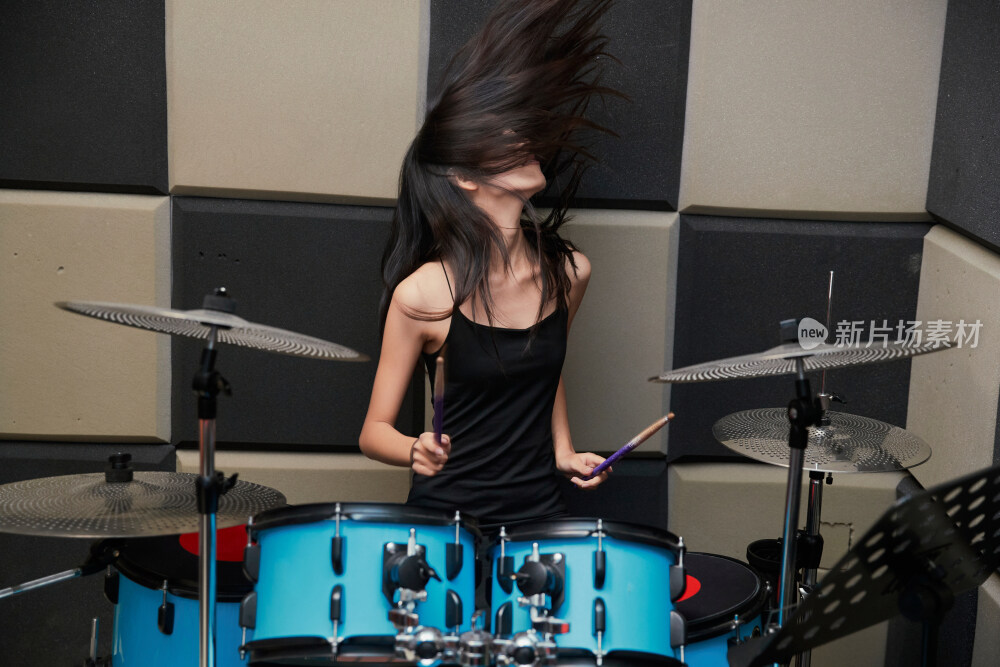 在排练室打爵士鼓的亚洲少女