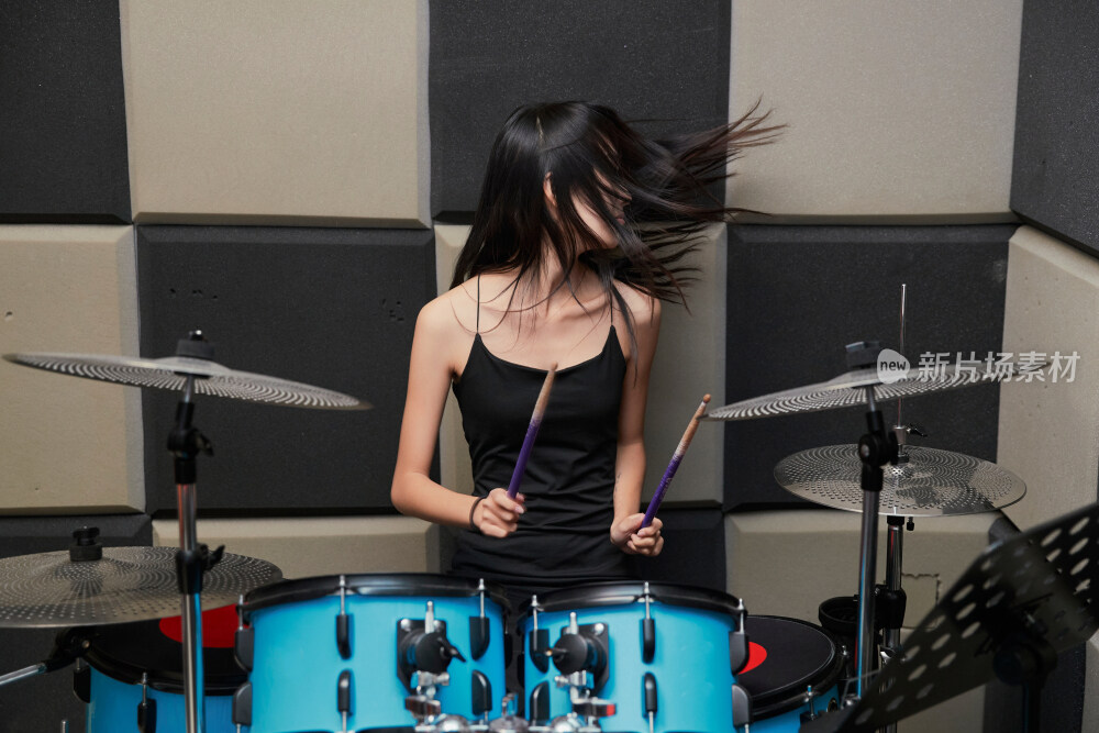 在排练室打爵士鼓的亚洲少女