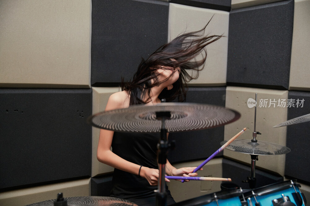 在排练室打爵士鼓的亚洲少女