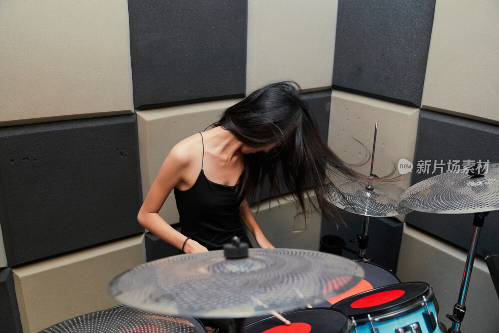 在排练室打爵士鼓的亚洲少女