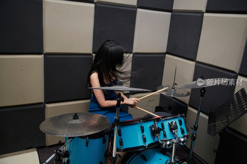 在排练室打爵士鼓的亚洲少女