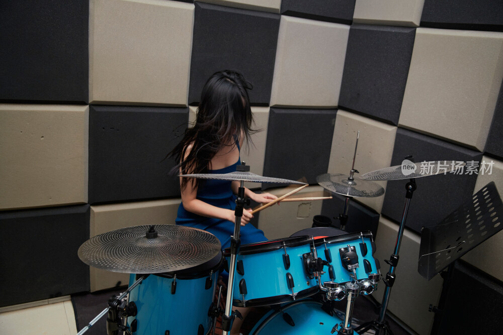 在排练室打爵士鼓的亚洲少女