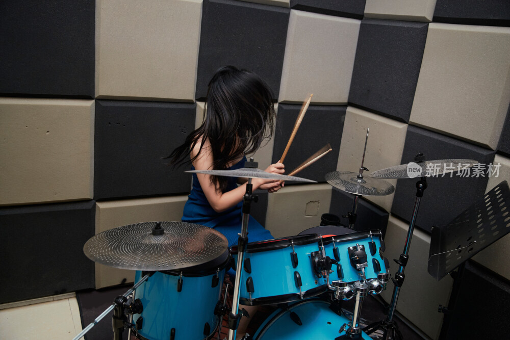 在排练室打爵士鼓的亚洲少女