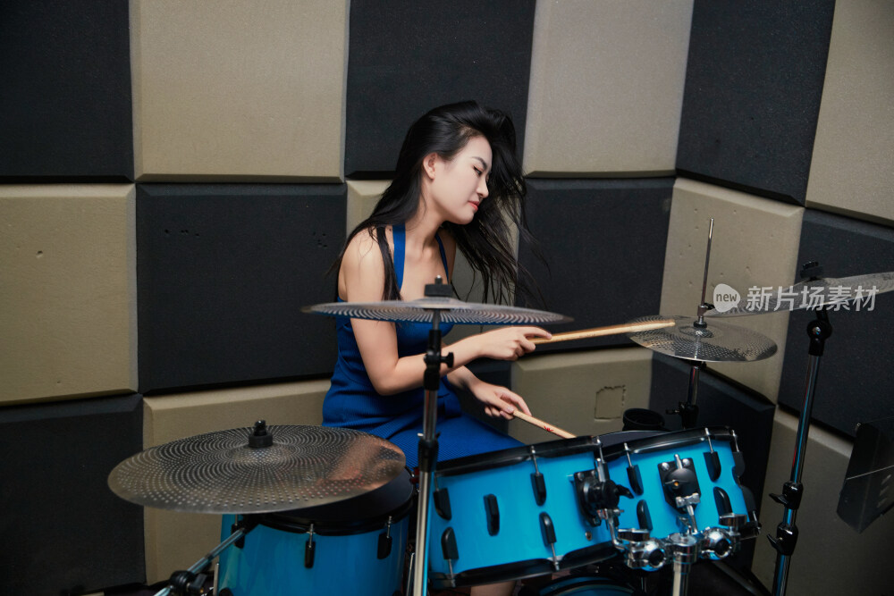 在排练室打爵士鼓的亚洲少女
