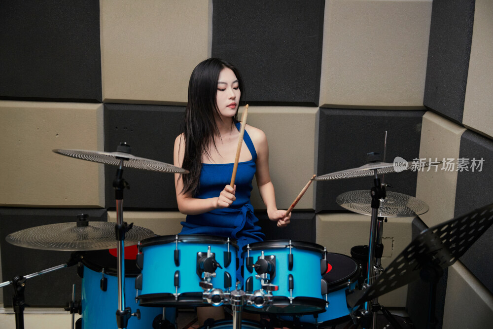 在排练室打爵士鼓的亚洲少女