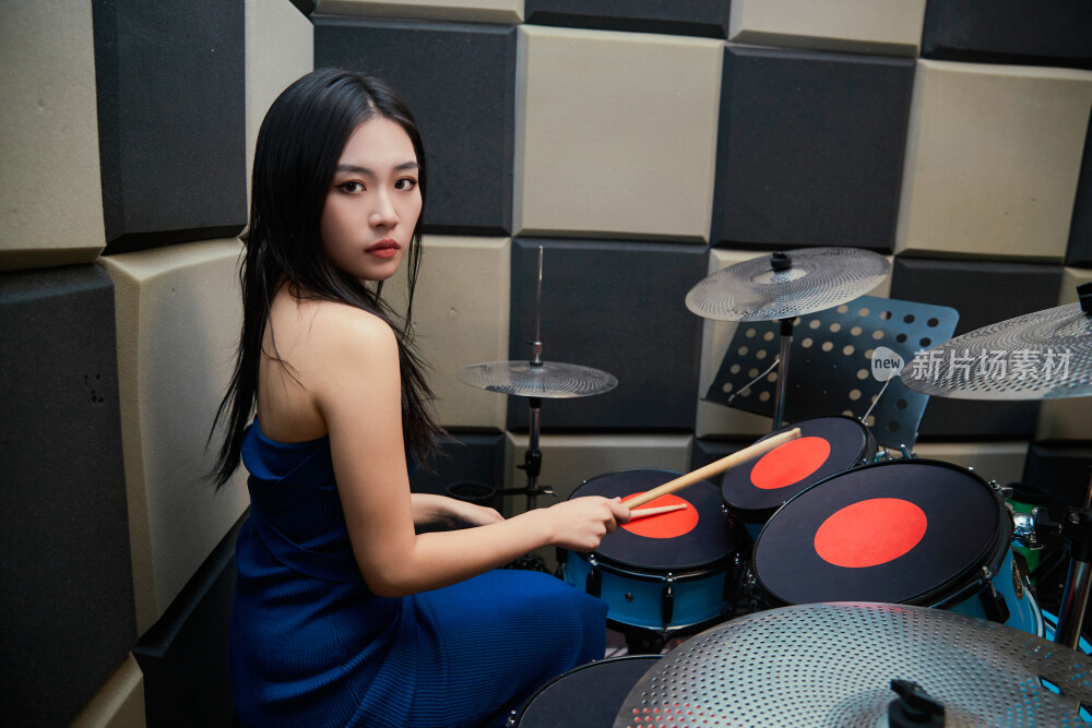 在排练室打爵士鼓的亚洲少女