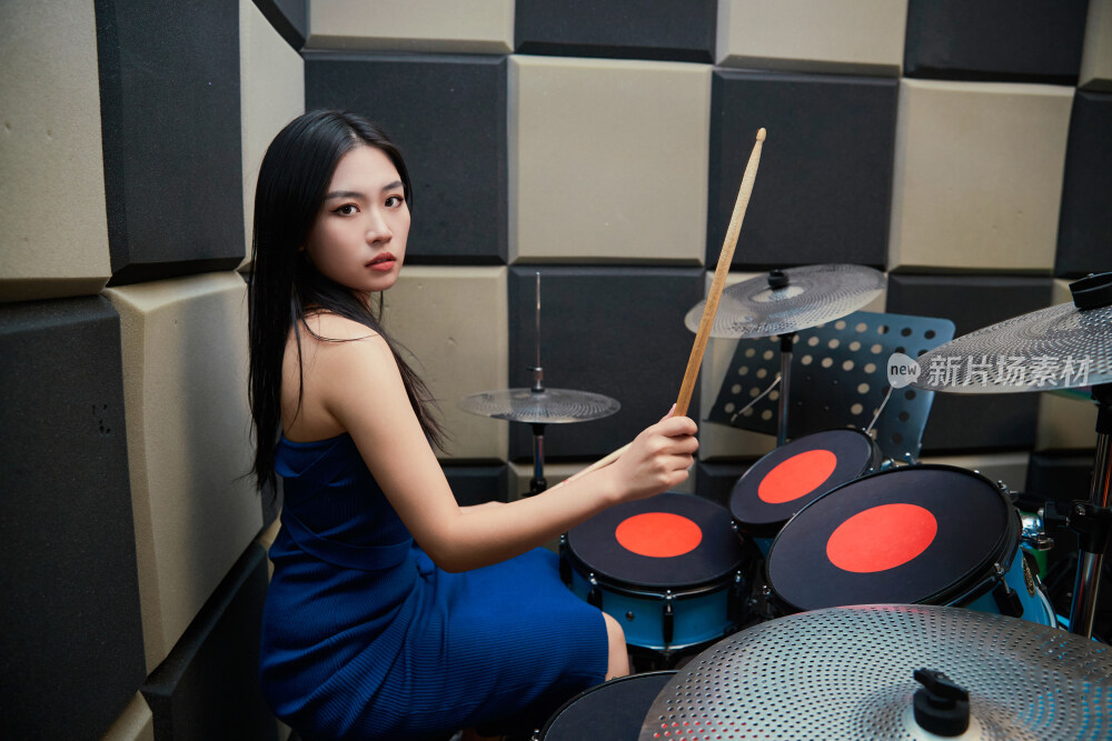 在排练室打爵士鼓的亚洲少女