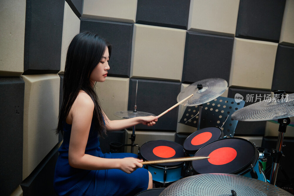 在排练室打爵士鼓的亚洲少女