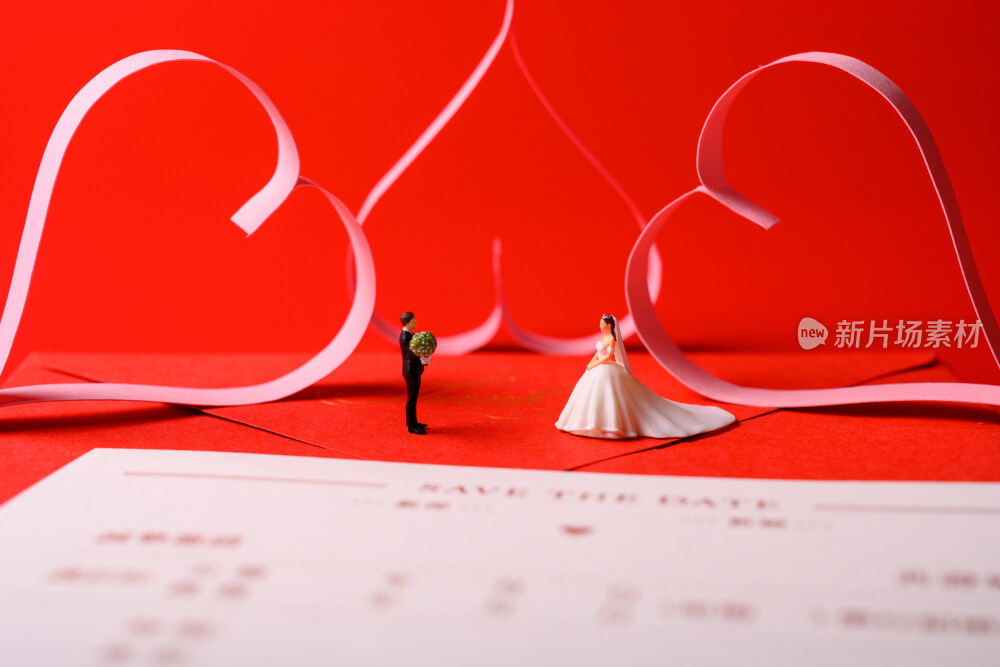 红色背景上放着的婚礼请柬和微缩景观婚礼