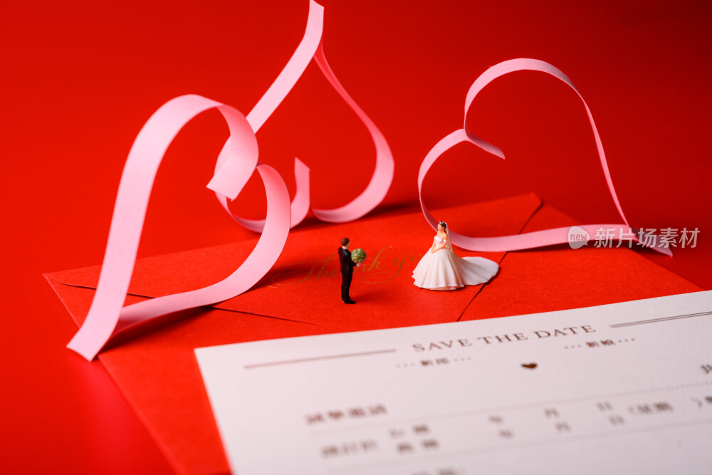 红色背景上放着的婚礼请柬和微缩景观婚礼
