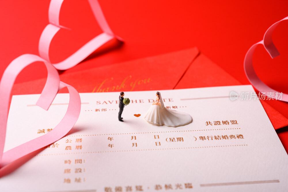 红色背景上放着的婚礼请柬和微缩景观婚礼
