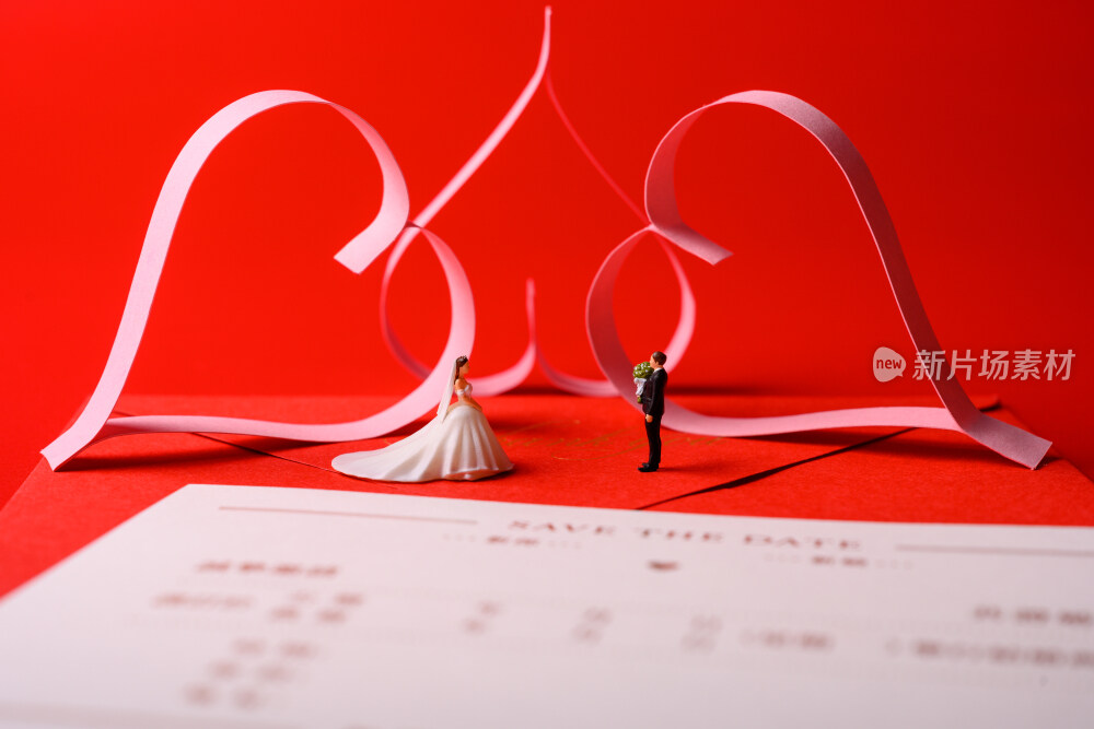 红色背景上放着的婚礼请柬和微缩景观婚礼