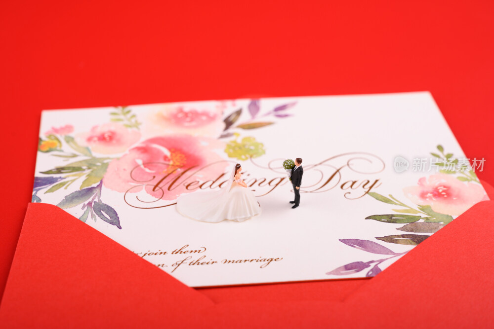 红色背景上放着的婚礼请柬和微缩景观婚礼