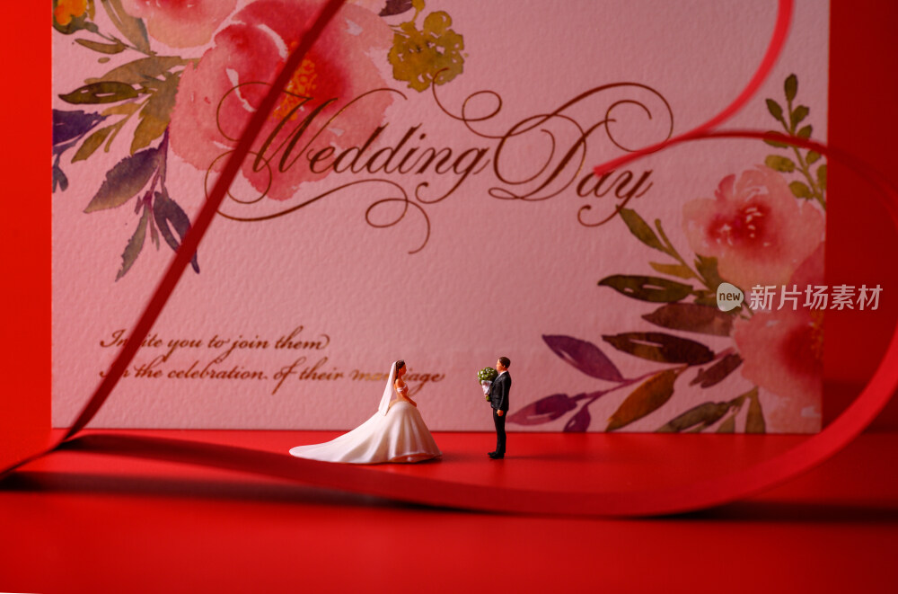 红色背景上放着的婚礼请柬和微缩景观婚礼