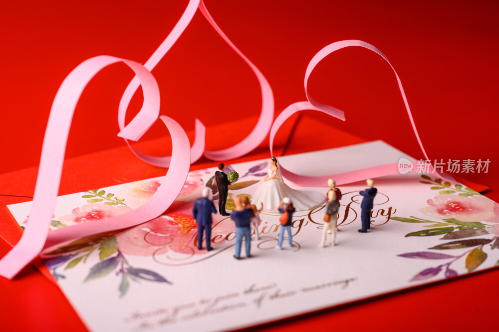 红色背景上放着的婚礼请柬和微缩景观婚礼