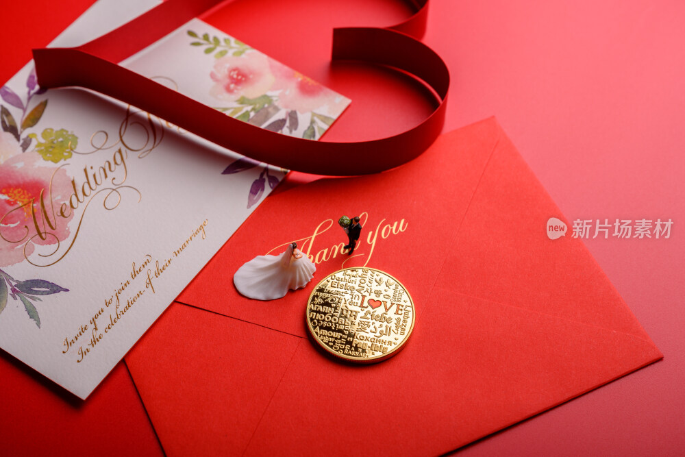 红色背景上放着的婚礼请柬和微缩景观婚礼