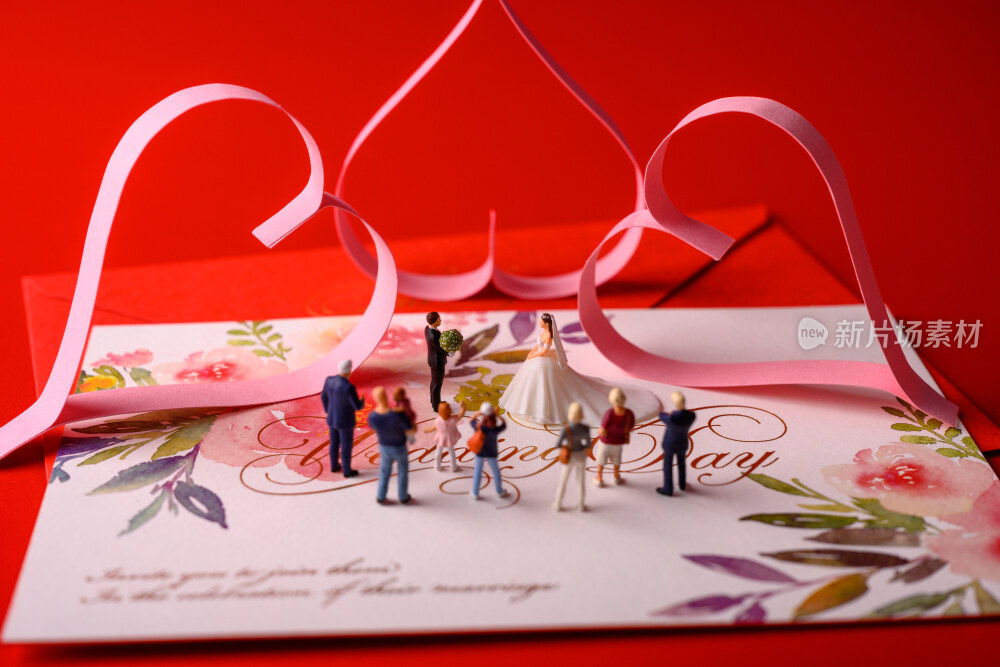 红色背景上放着的婚礼请柬和微缩景观婚礼