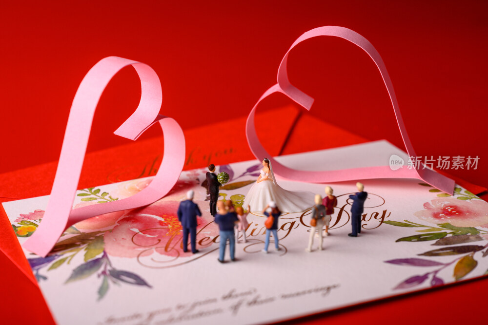 红色背景上放着的婚礼请柬和微缩景观婚礼