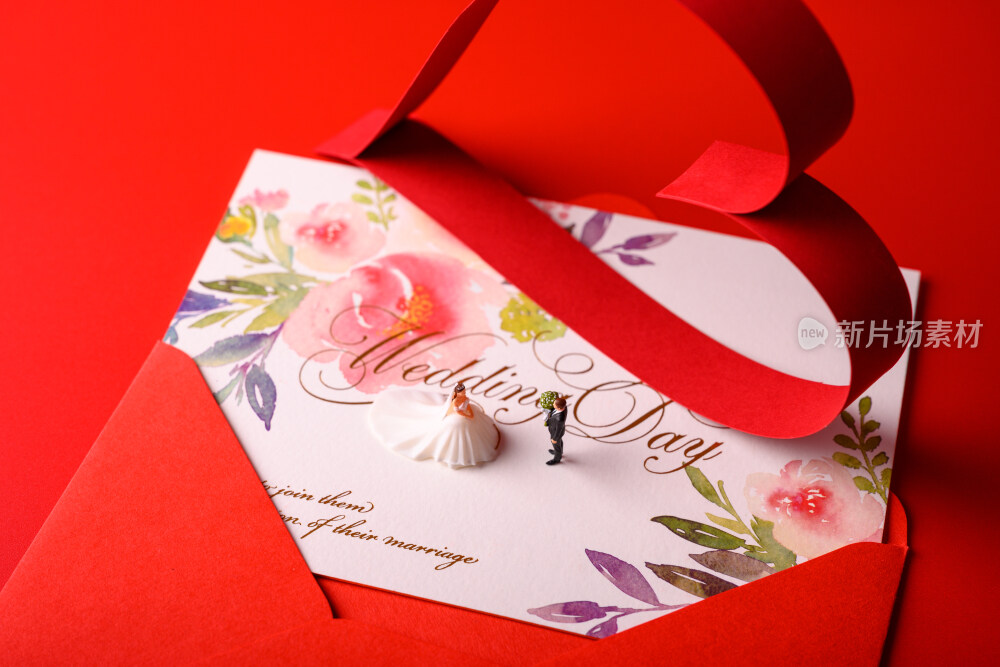 红色背景上放着的婚礼请柬和微缩景观婚礼