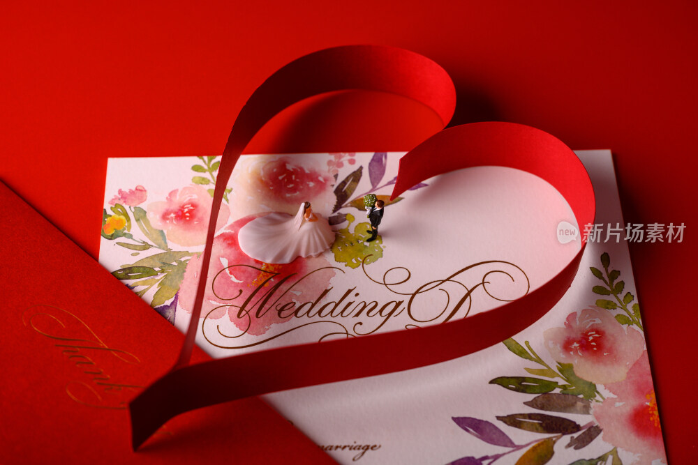 红色背景上放着的婚礼请柬和微缩景观婚礼