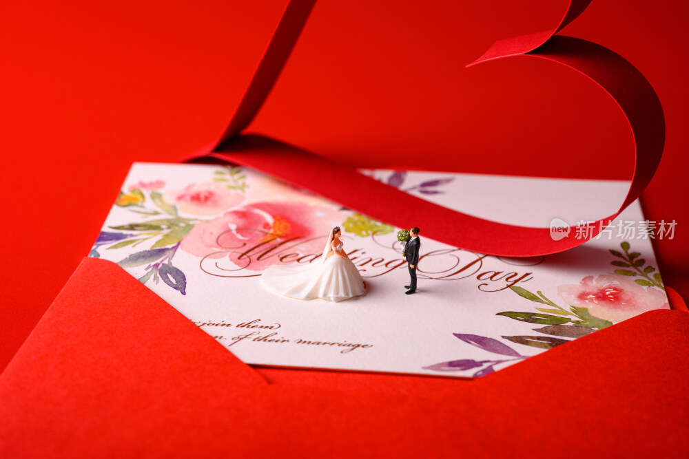 红色背景上放着的婚礼请柬和微缩景观婚礼